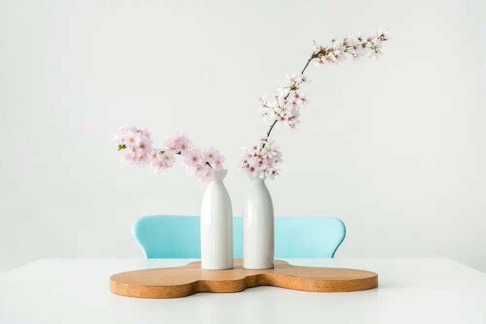 White ceramic vases holding spring blossoms on a wooden tray